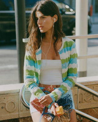 Woman wearing a green and blue striped cardigan over a white top, part of the Organic Basics Summer Layers collection